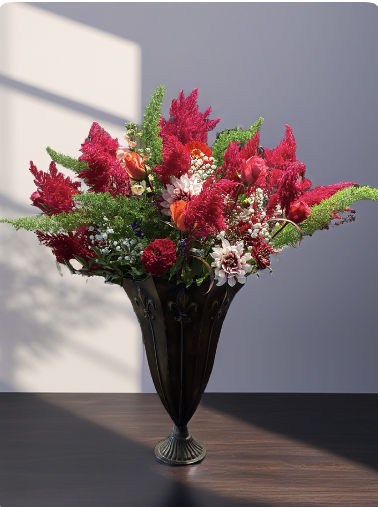 A dramatic arrangement of crimson celosia and blush flowers in a footed bronze compote